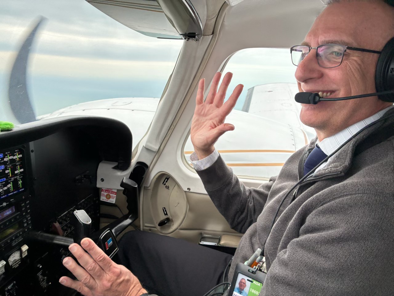 Tim Walker waving from the cockpit window of an aircraft